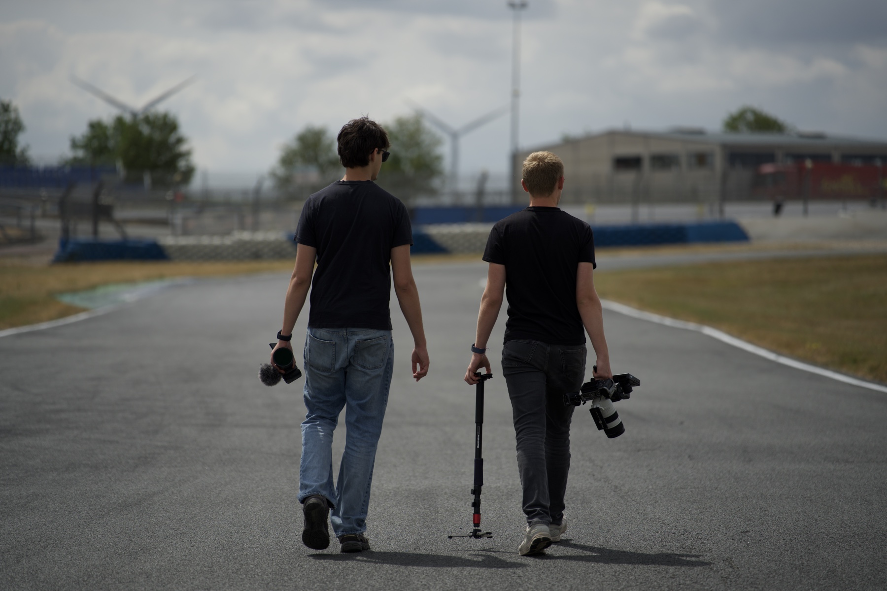 Lucas et un collègue de dos sur un circuit, caméra et matériel à la main